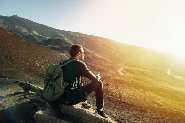 homme-sac-dos-assis-rocher-au-coucher-du-soleil-volcan-etna-montagne-sicile_8353-6518.jpg