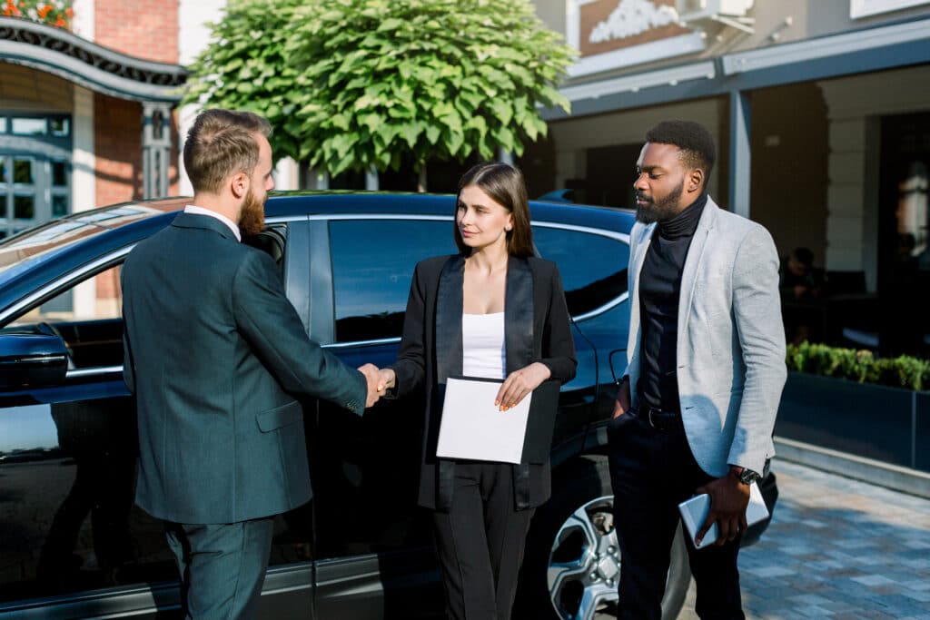 business-people-shaking-hands-finishing-up-meeting-caucasian-man-and-woman-shaking-hands-african-man-coworker-stands-and-holds-tablet-meeting-outdoors-near-the-car-1024x683-1.jpg